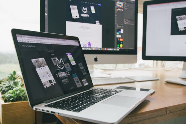 Workspace with laptop and monitors displaying design software